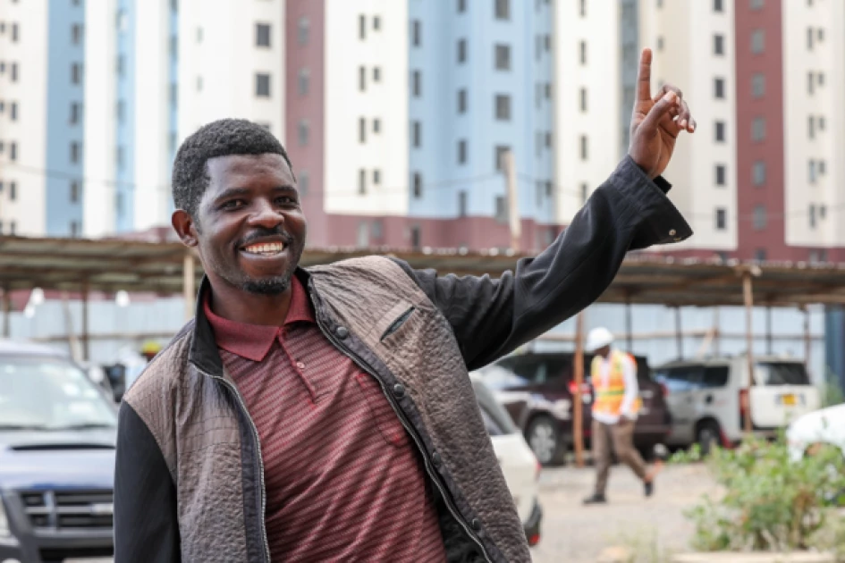 Geofrey Odhiambo, Chairman of the Mukuru Affordable Housing Beneficiaries Association, pointing at the newly constructed housing units.